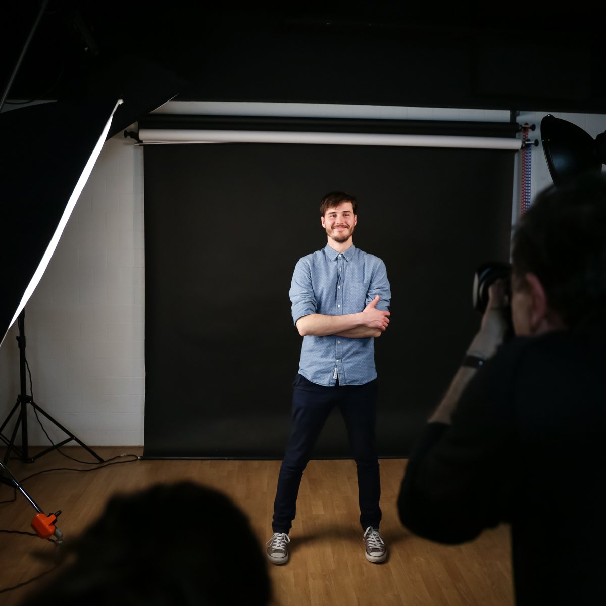 Jeune homme posant devant un photographe, en studio.